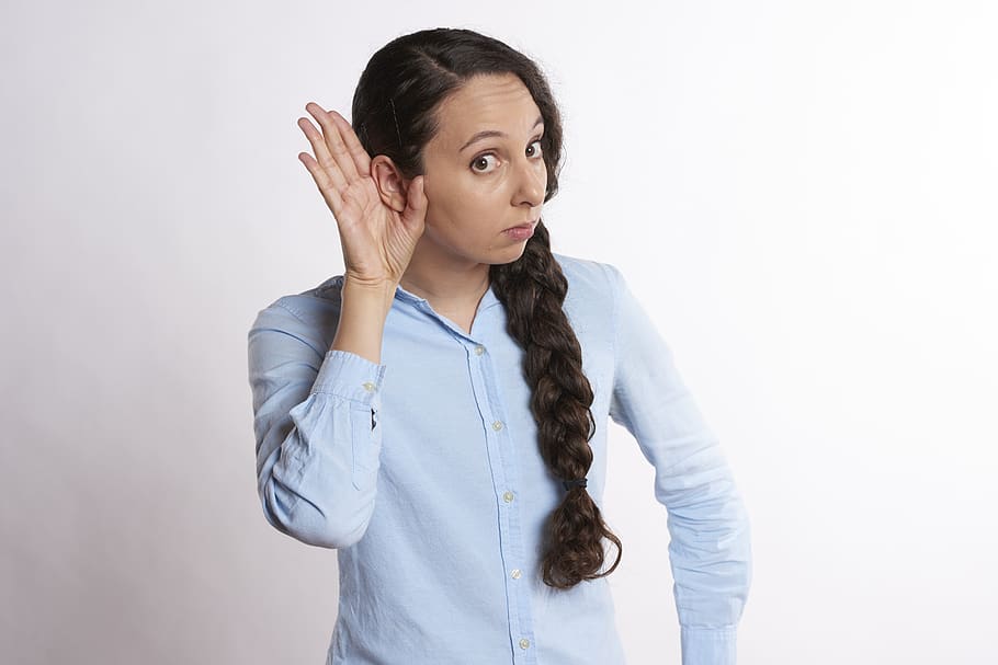 Woman With Her Hand On her Ear Listening
