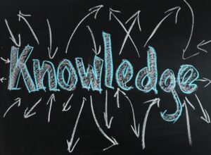 The word "knowledge" as written on a chalkboard with arrows going out and coming in.